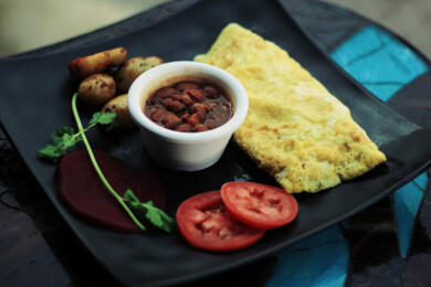 Egg omelet with a side of tomatoes and beans served on black plate